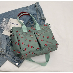 Detail of green tote bag with red cherry prints and functional dual front zippers