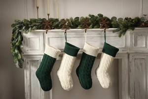 Close-up of cable knit Christmas stockings in cream and green hanging on a fireplace