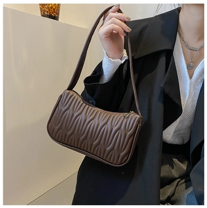 Detail shot of a dark brown underarm bag featuring elegant wavy quilted stitching and gold hardware