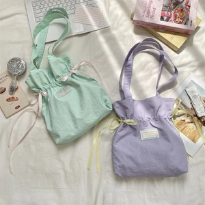 Detailed close-up of drawstring canvas tote bags in mint green and light purple colors