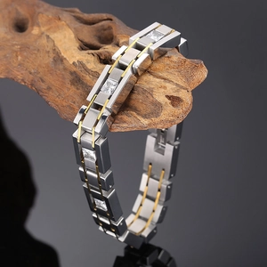 Detail of silver brushed steel chain bracelet with gold accents and cubic zirconia