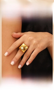Detail of wide golden ring with hammered texture in geometric square design