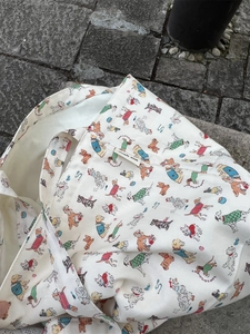 Close-up of cute cartoon dog prints and logo tag on a white canvas tote bag