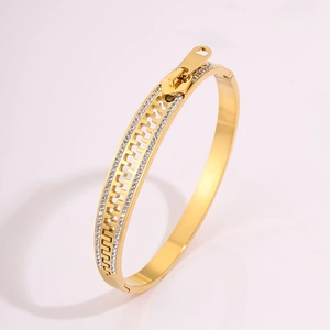 Close-up of golden zipper bangle with inlaid crystals and polished finish on metal