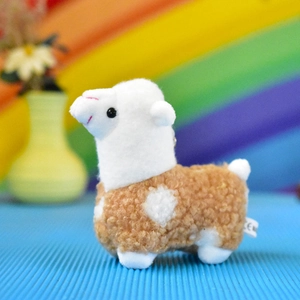 Macro detail of a small white and brown curly plush alpaca toy keychain for decoration