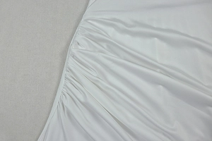 Detailed close-up of white satin dress fabric featuring delicate pleated texture and draping
