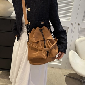 Sac seau en nylon marron avec cordon et bandoulière noire vu de côté sur un mannequin
