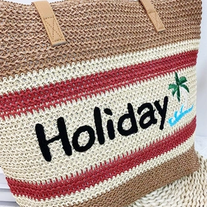 Detail of straw woven tote with Holiday embroidery and red stripes texture