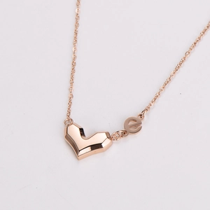 Close-up of rose gold necklace featuring geometric heart and lowercase e pendants