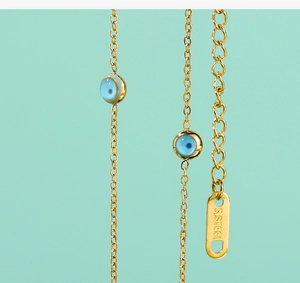 Macro view of blue evil eye beads on an 18K gold-plated stainless steel chain necklace