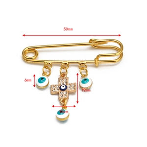 Detailed size view of a gold safety pin brooch with blue evil eye charms and rhinestones