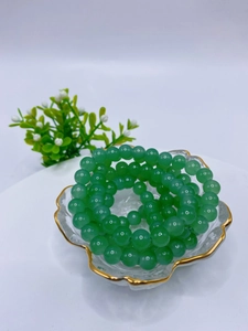 Detailed view of 8mm green glass beads bracelet placed in a decorative gold-rimmed bowl