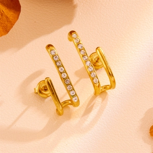 Detail of vintage gold U-shaped earrings with micro-set zircon stones on textured leather