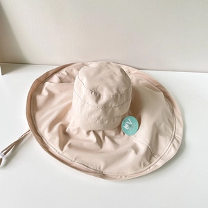 Detail of beige sun hat with UPF50+ tag, wide brim texture and adjustable chin strap