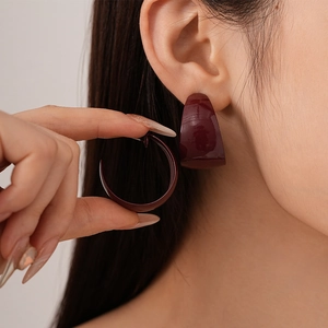 Close-up of vintage deep wine red C-shaped hoop earrings with a glossy finish on ear
