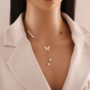 Collier papillon doré avec gemmes roses et perles blanches porté par un mannequin élégant