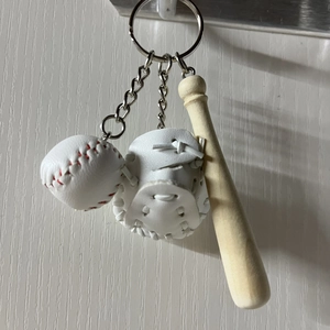 Detailed view of mini baseball, glove, and wooden bat pendant keychain set on wood