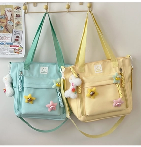 Detail of nylon shoulder bags in mint and yellow with star charms and plush pendants