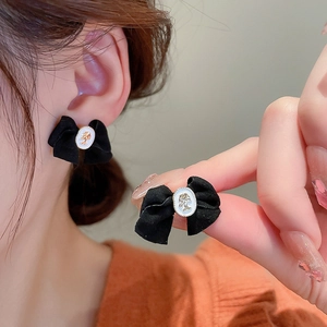 Close-up of black velvet bow earrings featuring a vintage gold-trimmed cameo portrait