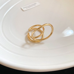 Macro shot of minimalist gold double-layered spiral ring on a textured white plate