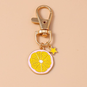 Detailed close-up of a yellow lemon slice keychain with a golden star charm and spring clip