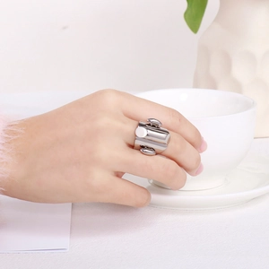 Close-up of a wide silver stainless steel ring worn by a model holding a cup