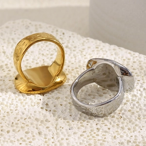 Irregular hammered 18K gold and silver stainless steel signet rings on white stone
