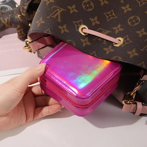 Putting a portable holographic pink laser jewelry box into a bag showing its compact size