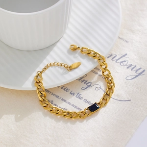 Close-up of golden stainless steel chain bracelet with a square black zircon stone on paper