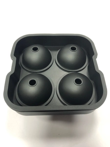 Close-up of a black four-hole spherical silicone ice ball mold with a clean white backdrop