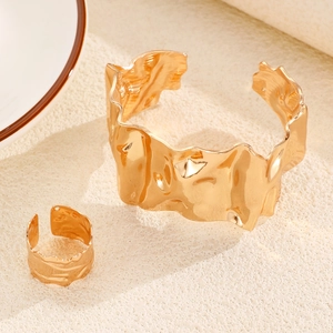 Detail of gold-tone lava textured cuff bracelet and matching ring with wavy edges