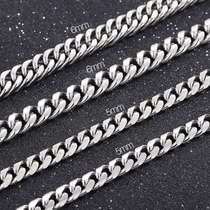 Detail view of 6mm and 5mm stainless steel Cuban link chains on a textured background