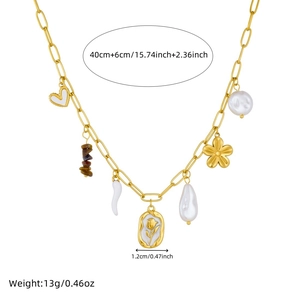 Detailed close-up of gold chain necklace with baroque pearl, heart and floral tulip charms
