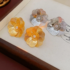 Detailed view of woven metal flower earrings in gold and silver with zircon center