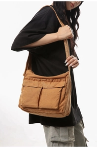Detailed side view of brown canvas messenger bag with large front utility pockets