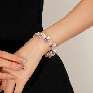 Detailaufnahme eines dehnbaren Armbands mit Emaille-Blumen am Handgelenk einer Frau