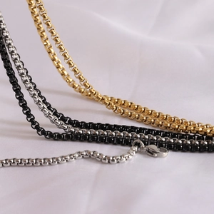 Close-up of stainless steel box chains in gold, black, and silver with lobster clasps