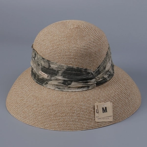 Detail of elegant woven sun hat featuring a tie-dye ribbon and UV protection tag
