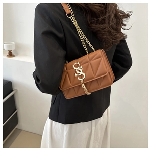 Detailed view of caramel quilted crossbody bag with gold chain and tassel hardware