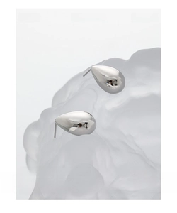 Macro shot of minimalist teardrop stud earrings with polished silver mirror finish