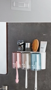 Detail of wall-mounted toothbrush holder with three frosted cups and storage shelf
