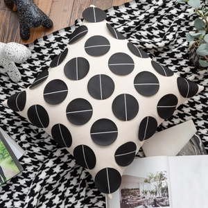Detail of beige square cushion with black leather circular patches on houndstooth blanket