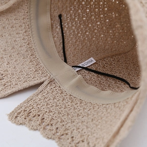 Close-up of beige knitted bucket hat interior with sweatband and black elastic chin strap