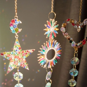 Detailed view of crystal suncatchers in heart and moon shapes reflecting rainbows