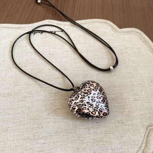 Detail of leopard print heart pendant with adjustable black cord and silver metal beads