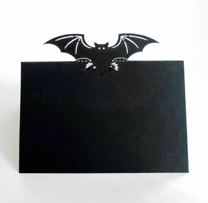 Detail of a matte black Halloween place card with a precision bat-shaped cutout design
