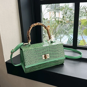 Close-up of green crocodile embossed texture with iconic bamboo handle and twist lock