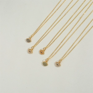 Set of five gold evil eye necklaces with colorful zircon pendants on textured surface