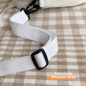 Détail de la bandoulière réglable en nylon blanc avec boucle noire et crochet métallique