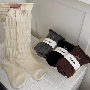 Détails de chaussettes en laine tricotées avec nœuds en crème, gris et marron